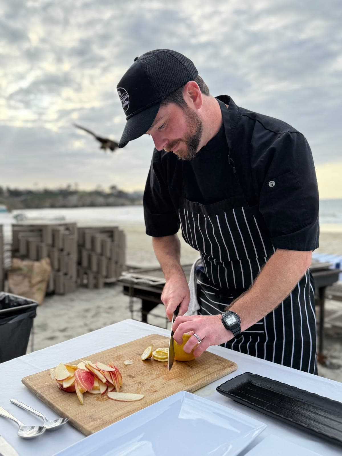 Chef Matt Brophy slicing citrus and apples at an outdoor prep table